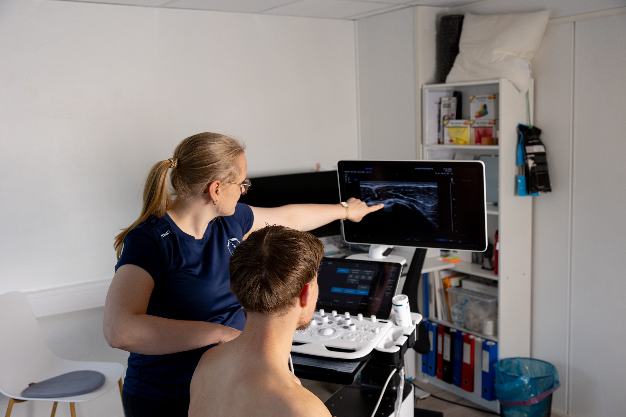 Fysioterapeut viser ultralyd på skjerm til pasient.